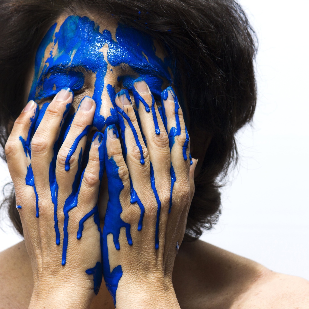 Лицо и руки женщины в синей краске