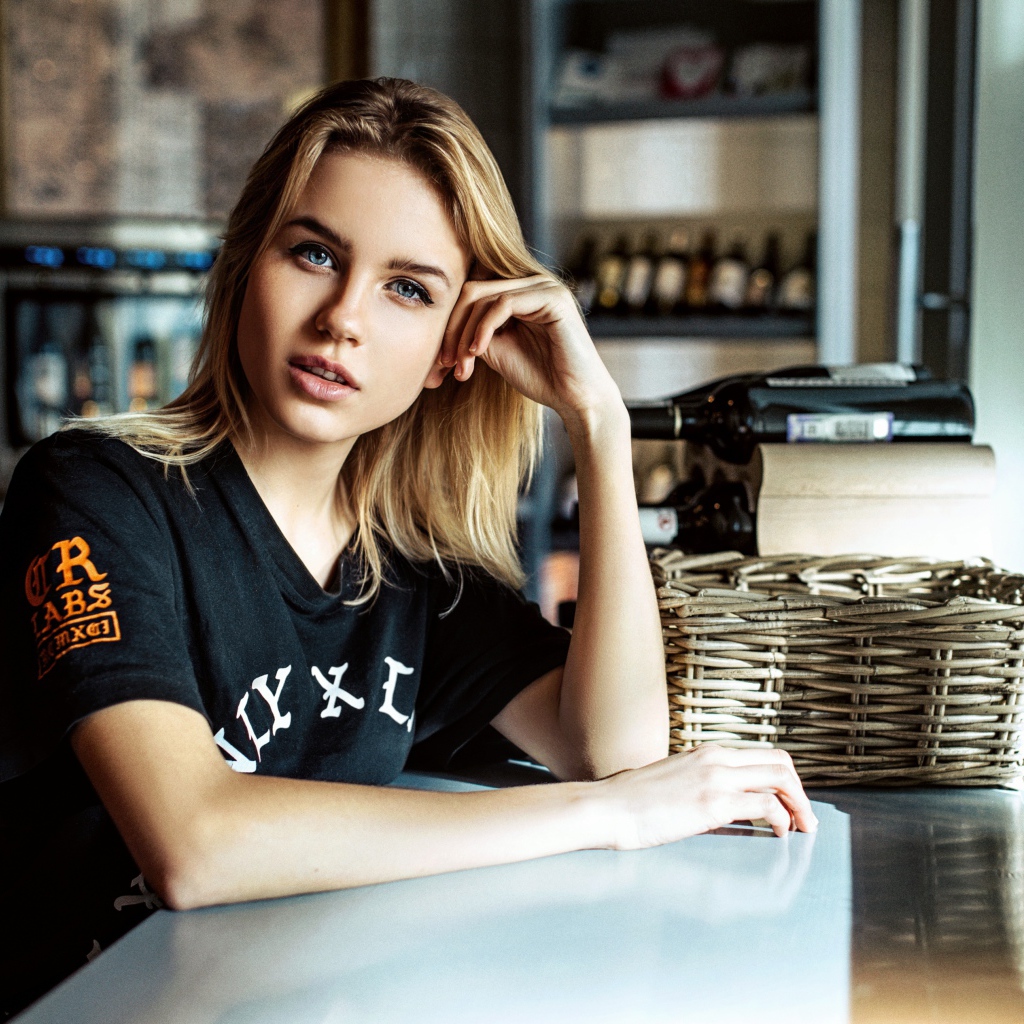 Молодая голубоглазая девушка сидит в кафе