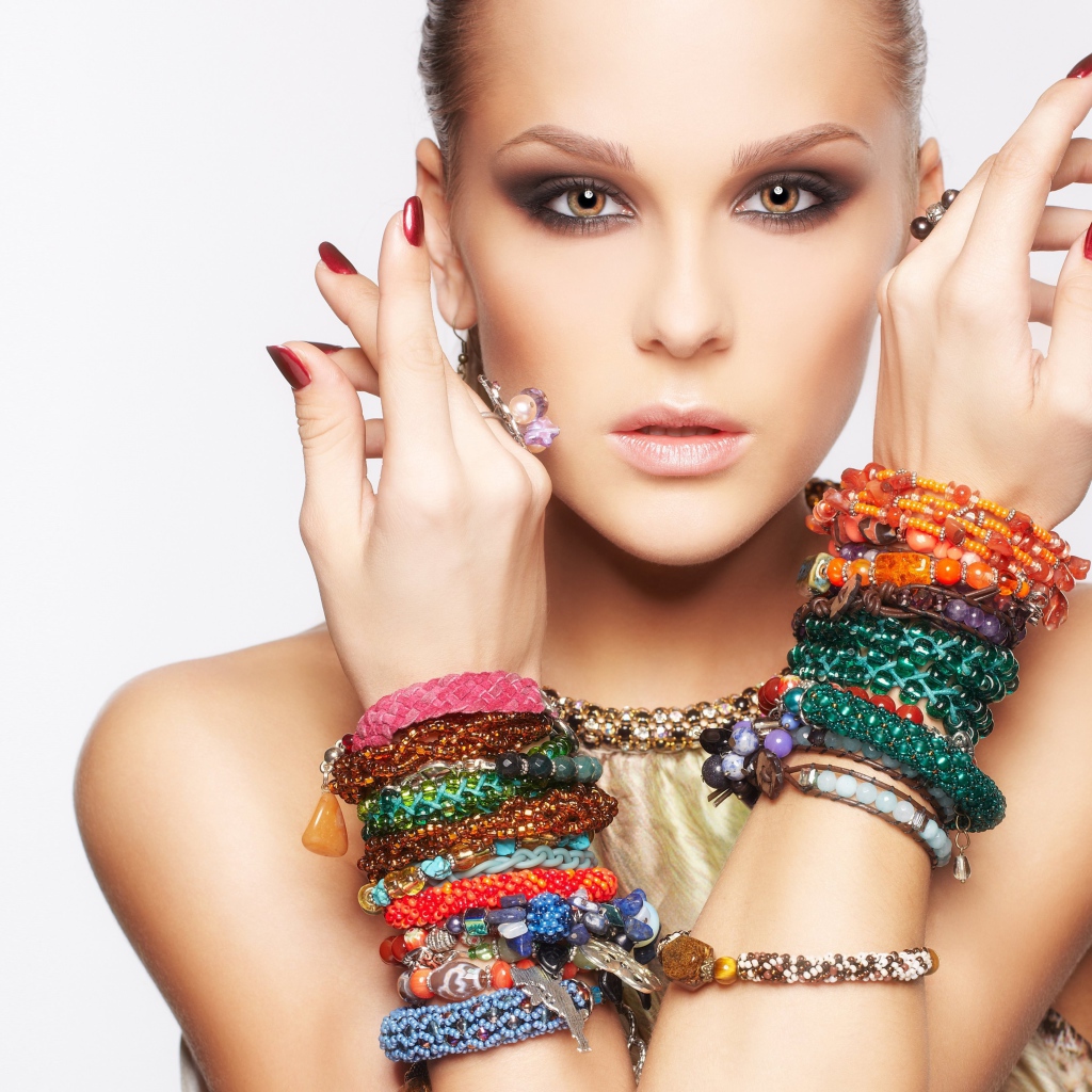 Молодая кареглазая девушка с браслетами на руках на белом фоне