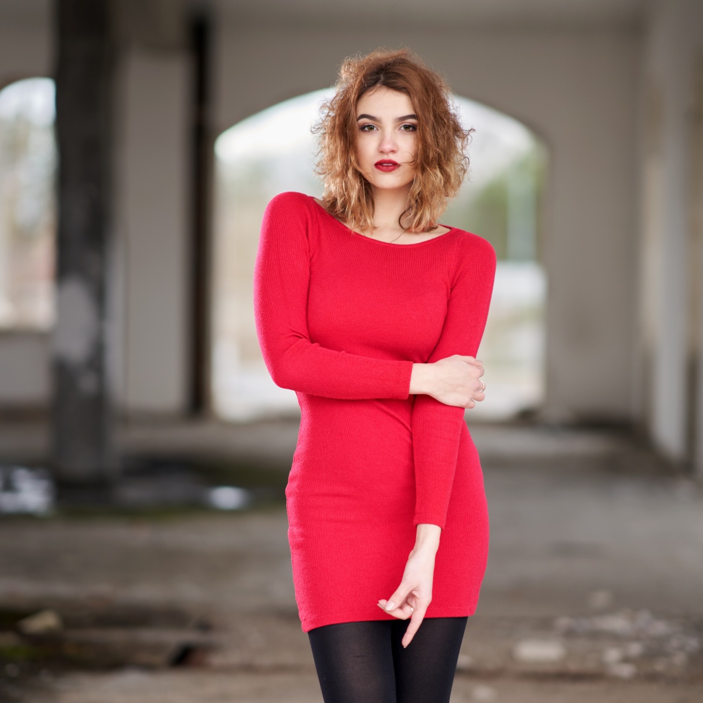 Молодая девушка в красном платье в старом здании