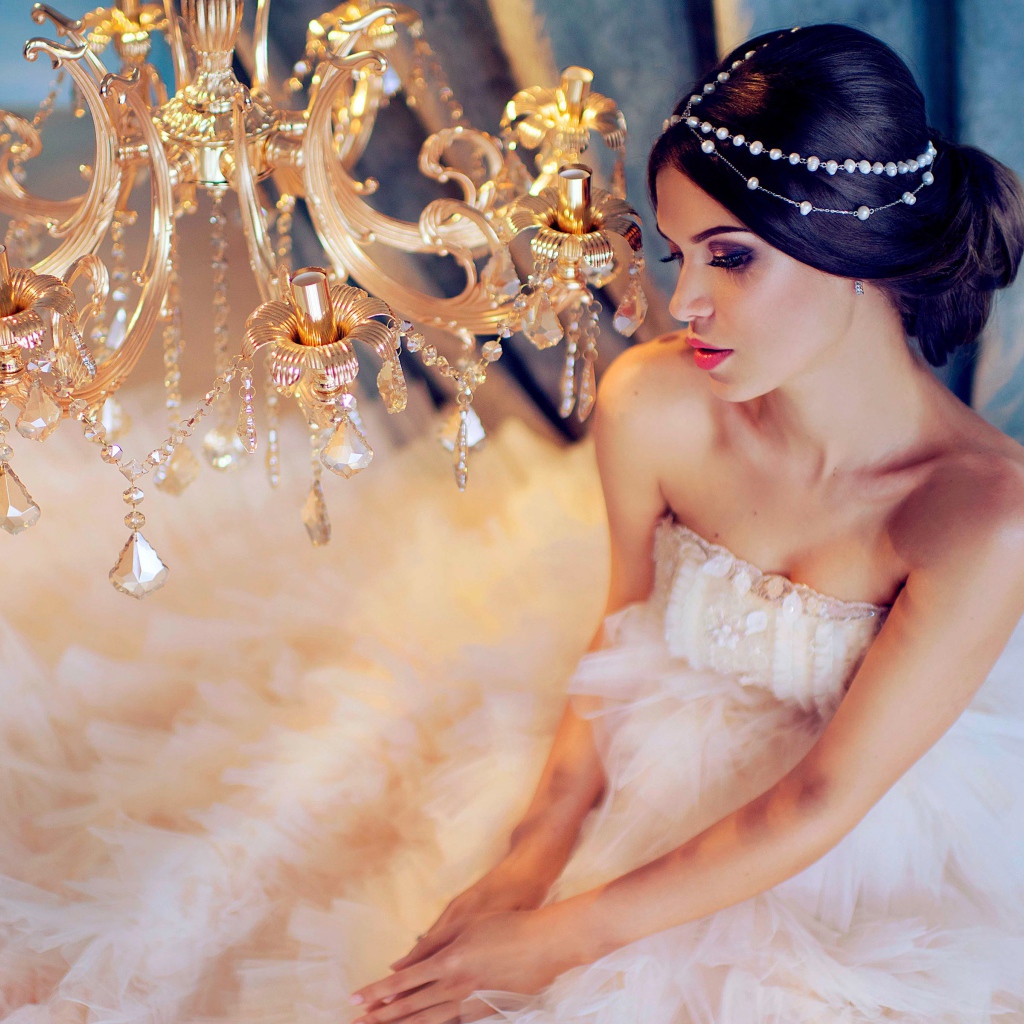 Молодая девушка в белом платье у красивой  люстры