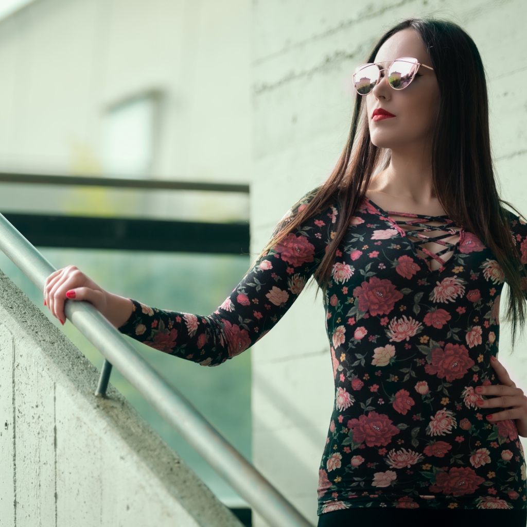 Молодая девушка в солнечных очках стоит на ступеньках