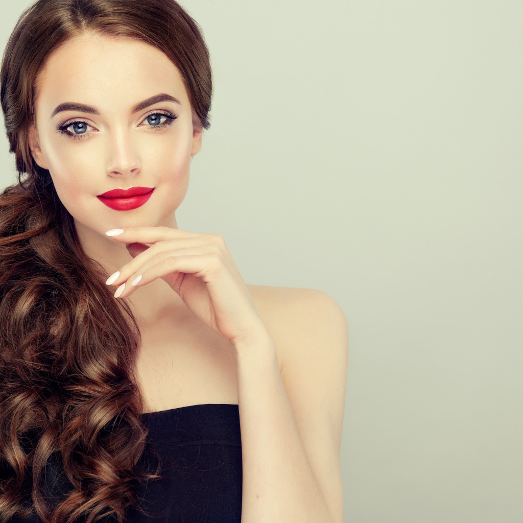 Молодая девушка с красивыми волосами на сером фоне