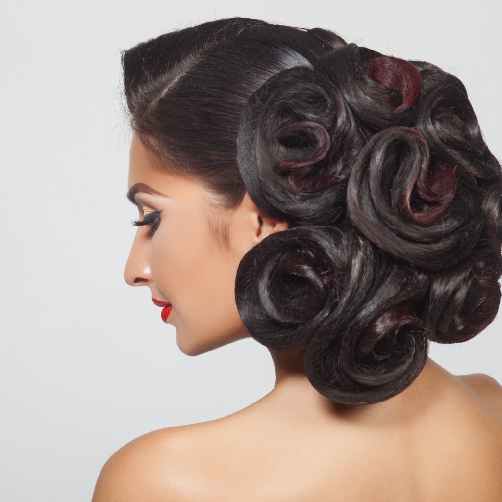 Молодая девушка с красивой прической на сером фоне