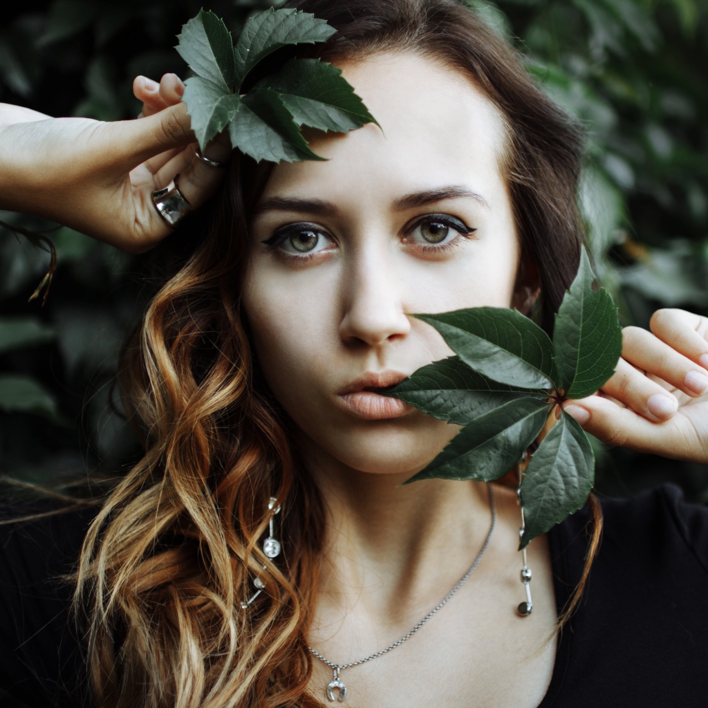 Молодая девушка с зелеными листьями в руках 
