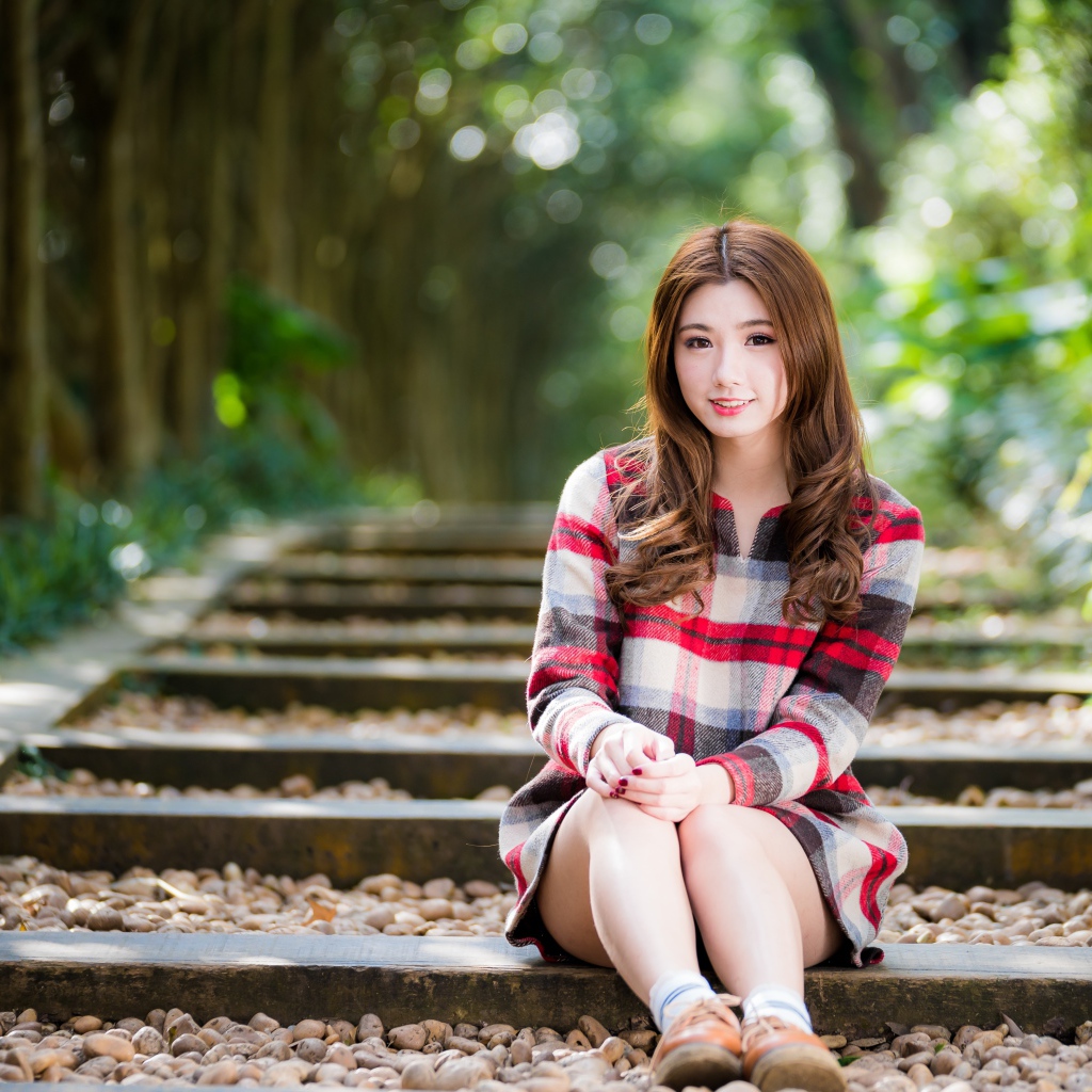 Молодая улыбающаяся азиатка сидит на дороге