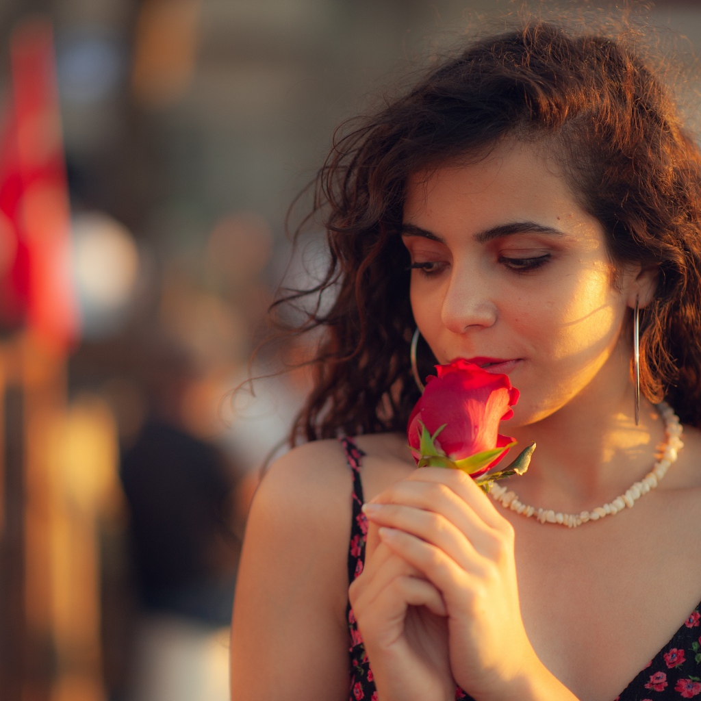 Молодая нежная девушка с красной розой в руке