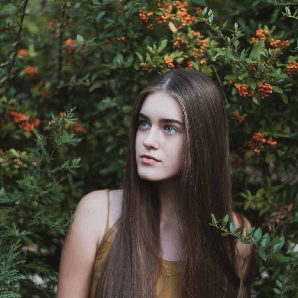 Молодая нежная девушка с длинными волосами в зеленых зарослях 