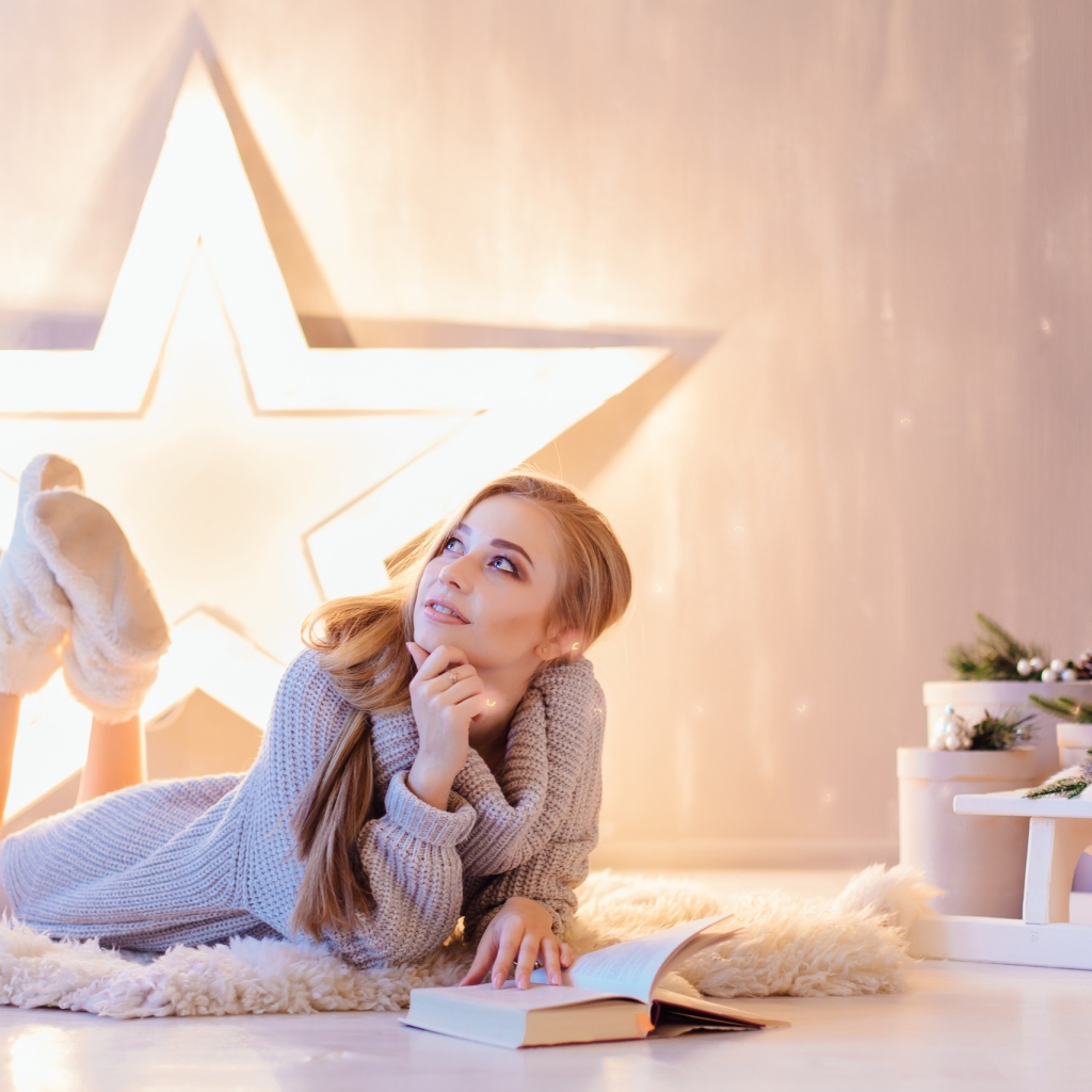 Красивая девушка читает книгу у новогодней елки