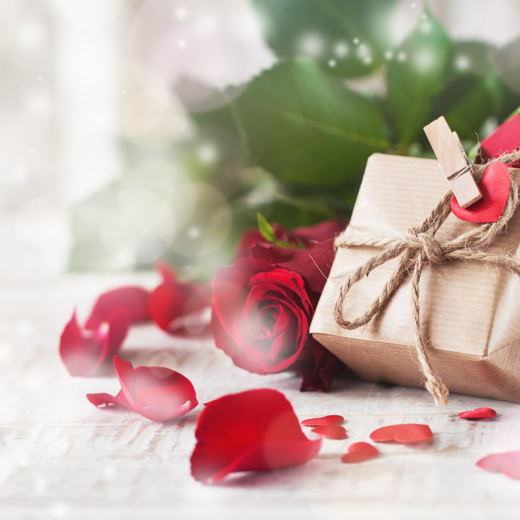 Подарок в коробке на столе с красными розами