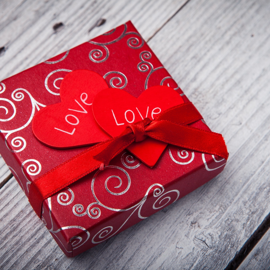 Подарок с красными сердечками на деревянном столе 