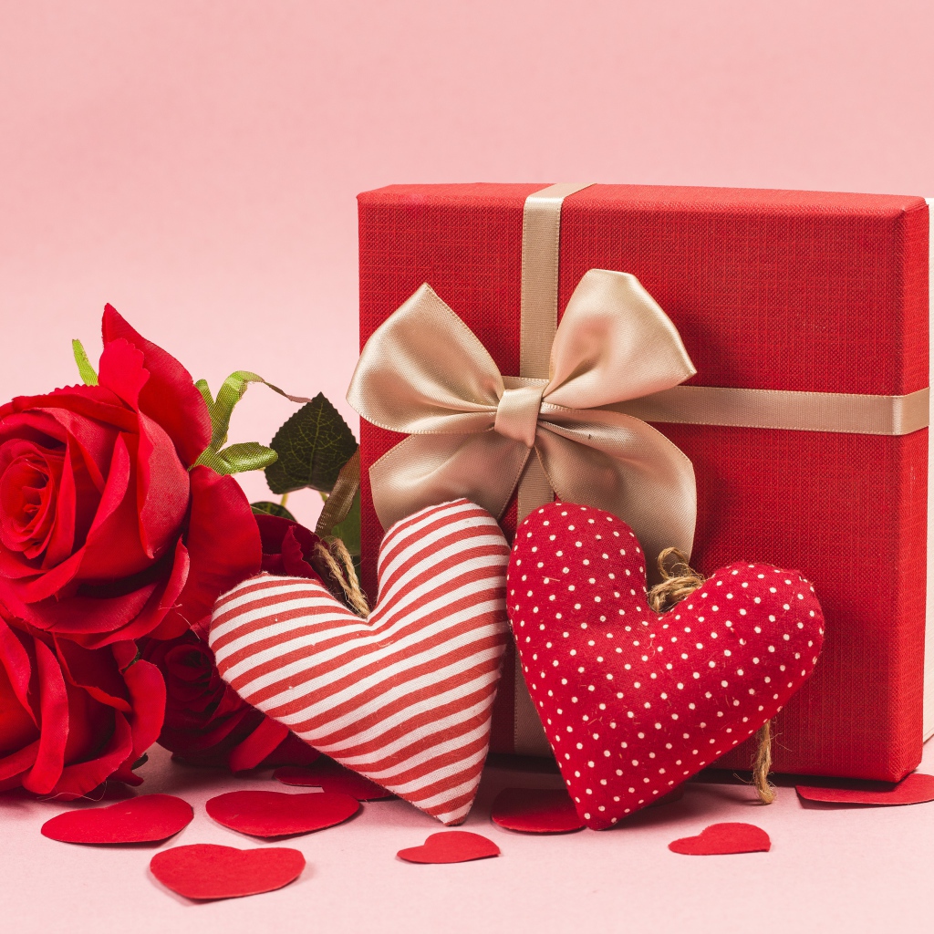 Три красные розы с сердечками и подарком на розовом фоне