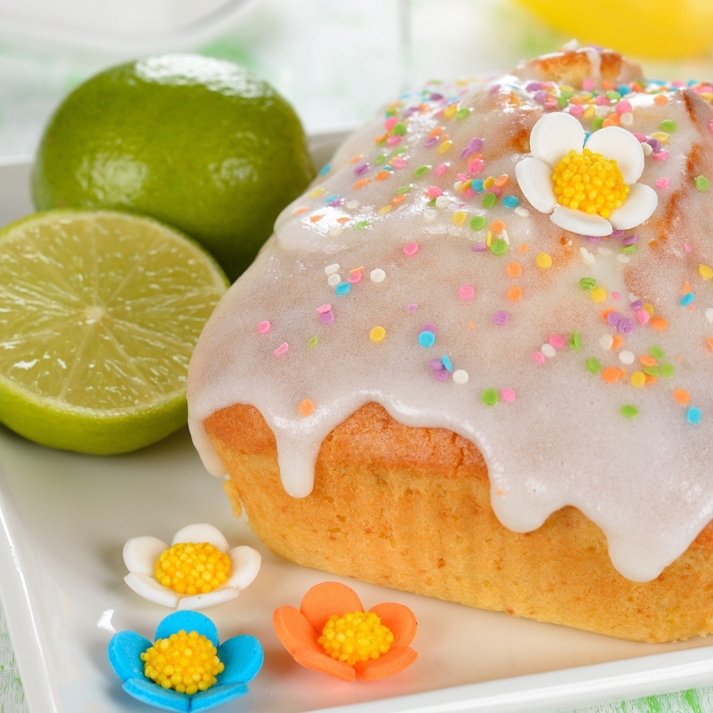 Красивый пасхальный кулич на белой тарелке с лаймом и сахарными цветами