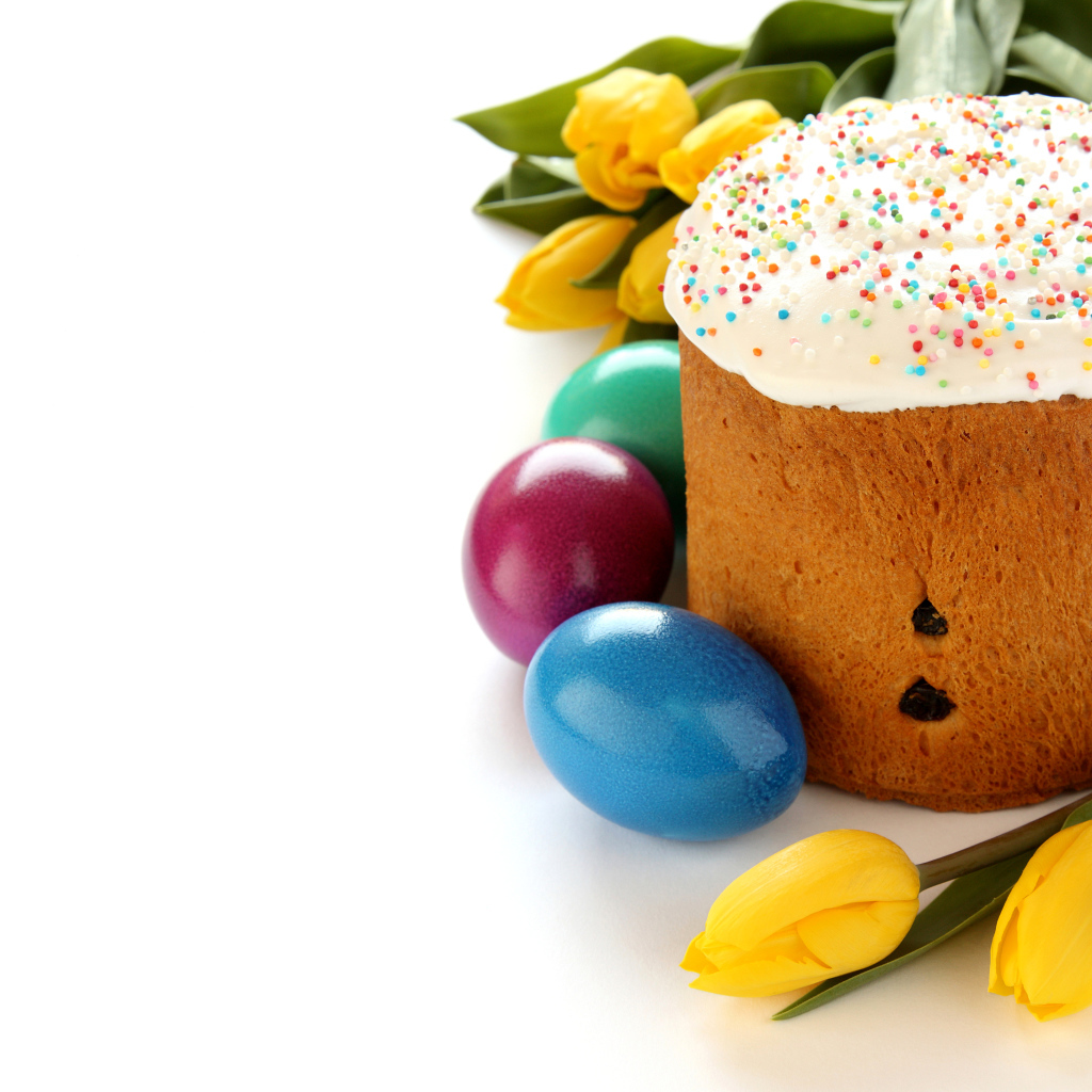 Красивый праздничный кулич с желтыми тюльпанами и крашеными яйцами на белом фоне к Пасхе