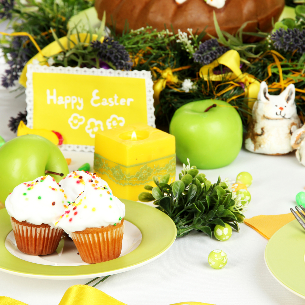 Накрытый пасхальный стол с кексами и зажженной свечой 