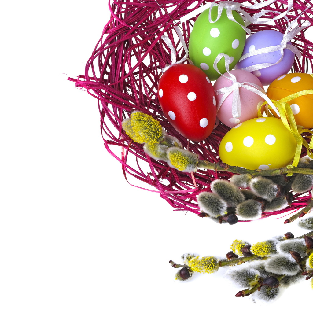 Крашеные пасхальные яйца в гнезде на белом фоне с веткой вербы