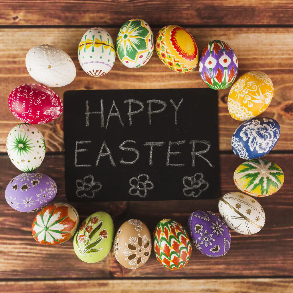 Надпись на английском Счастливой Пасхи на столе с крашеными яйцами