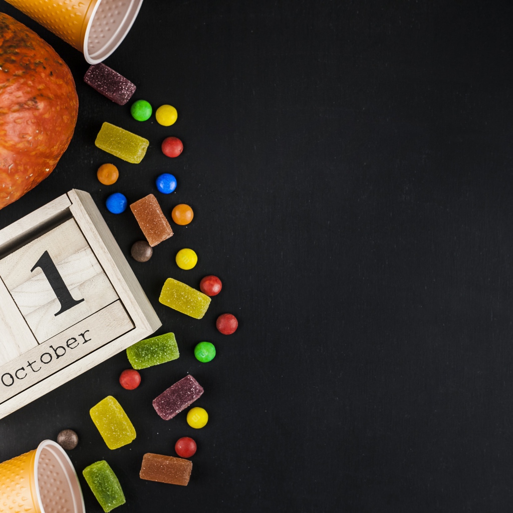 Конфеты, тыква и календарь на сером фоне на Хэллоуин