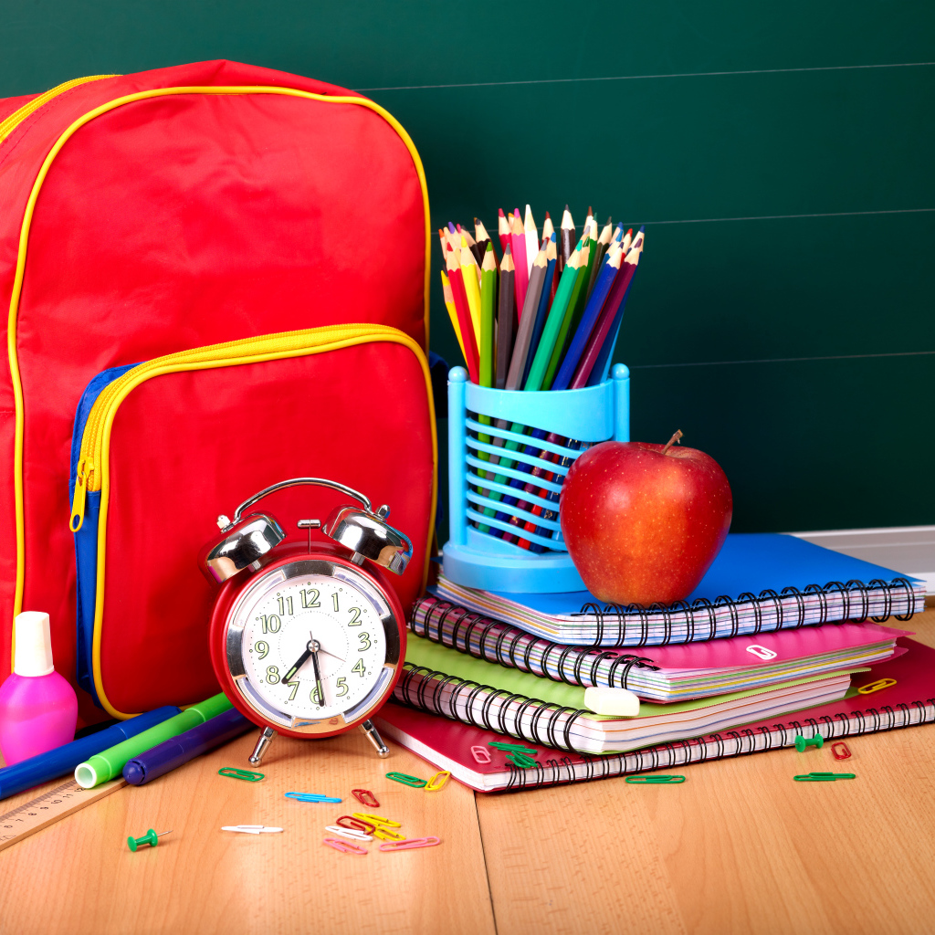 Рюкзак, тетради, карандаши, будильник и яблоко на День знаний 1 сентября
