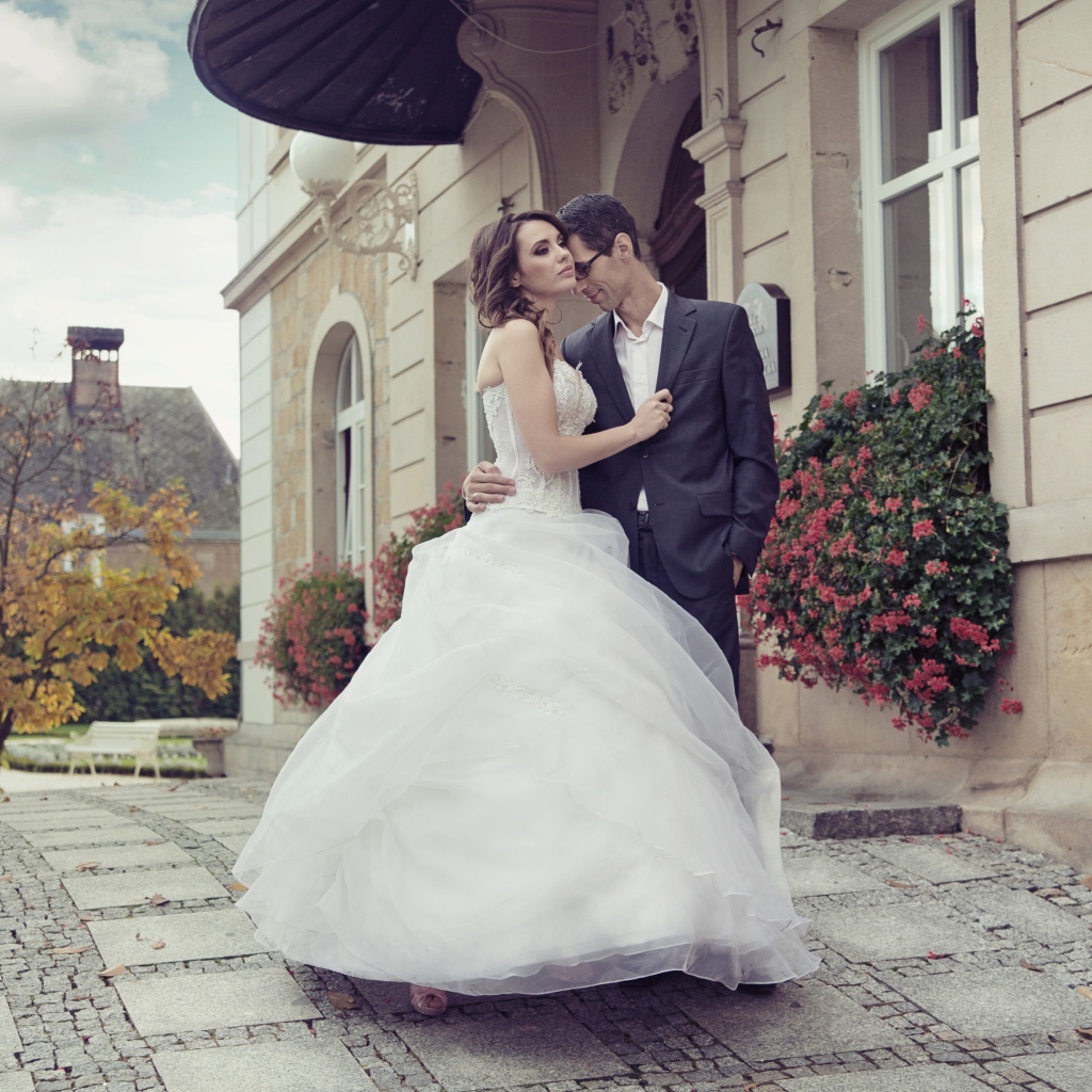 Жених и невеста стоят у здания 