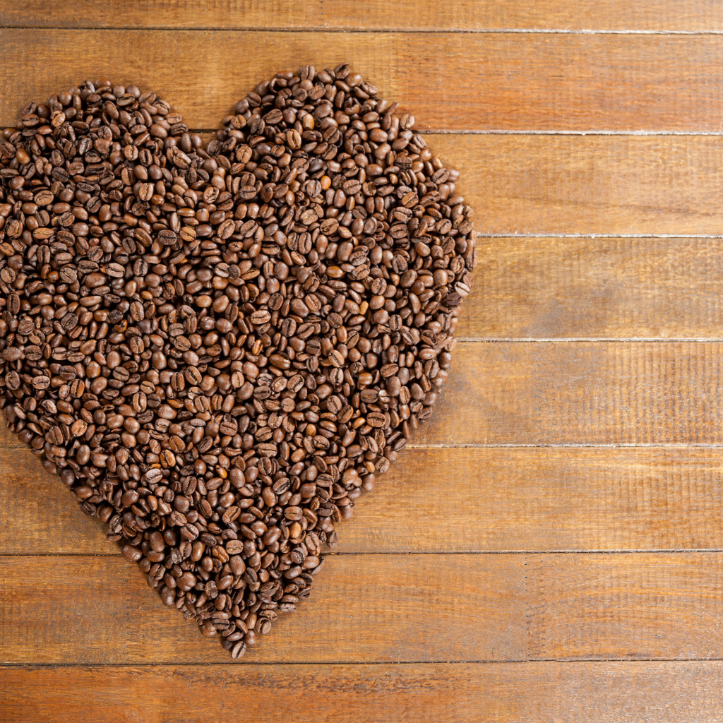 Большое сердце из кофейных зерен на деревянном столе