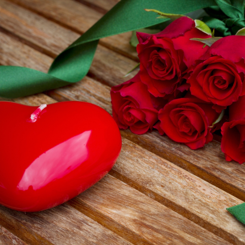 Большое сердце на деревянном столе с букетом красных роз 