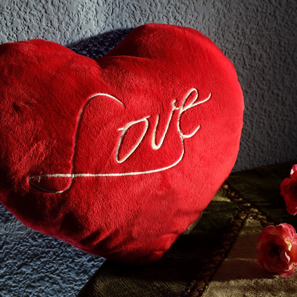 Большое плюшевое красное сердце у стены 