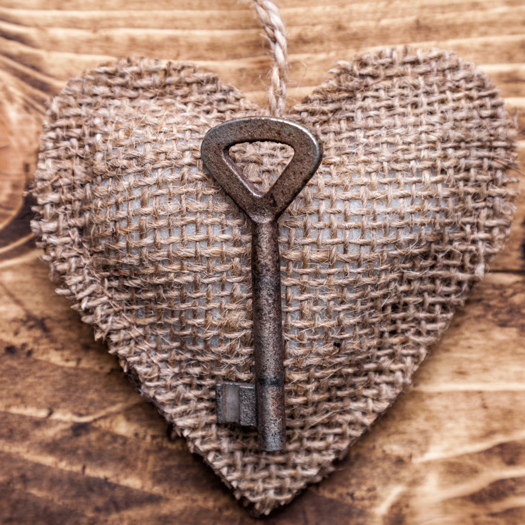 Сердечко из мешковины с ключом на деревянном фоне