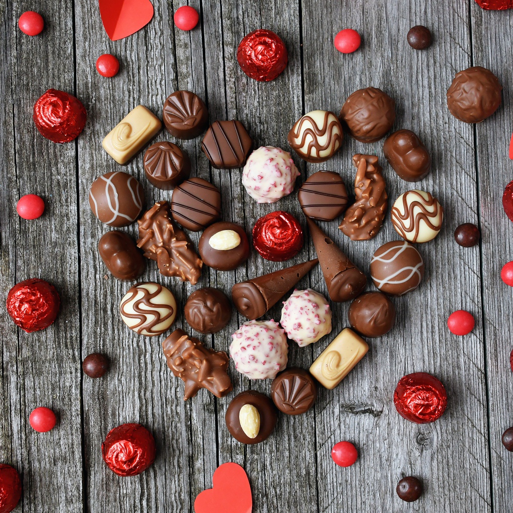 Сердце из шоколадных конфет ассорти на деревянном столе для любимой 