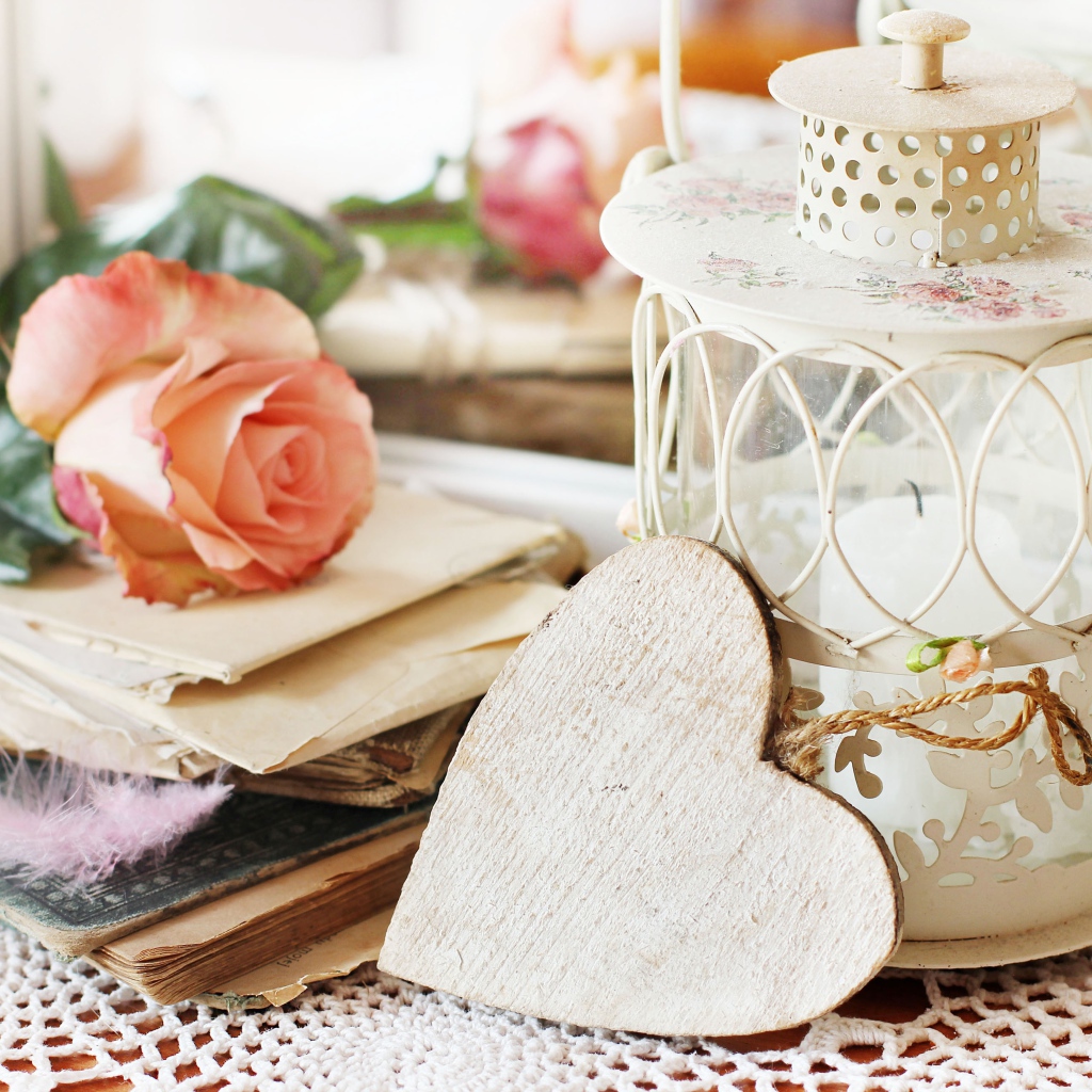 Фонарь со свечей на столе с розой, сердцем и книгами