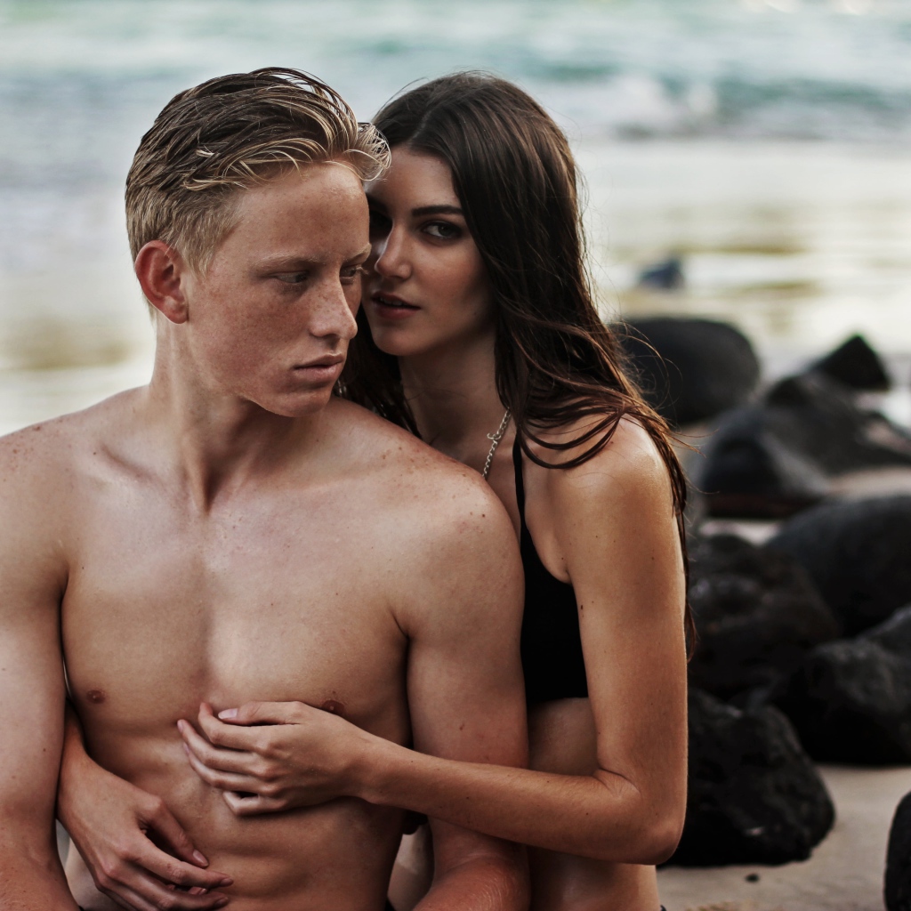 Влюбленная пара сидит на камнях на берегу моря 