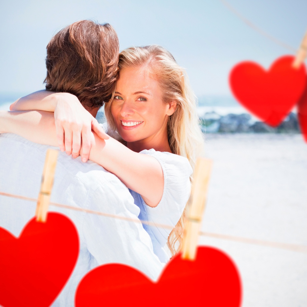 Влюбленная пара с красными сердечками на берегу океана