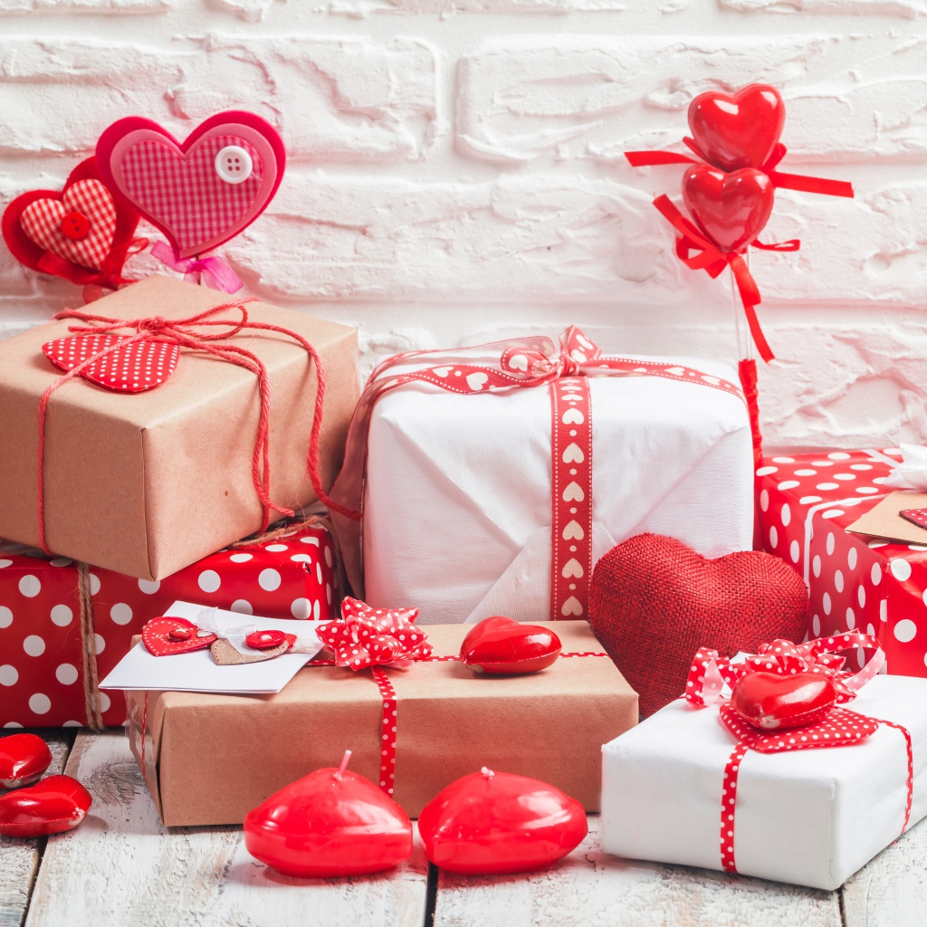 Много  подарочных коробок с сердечками на фоне стены