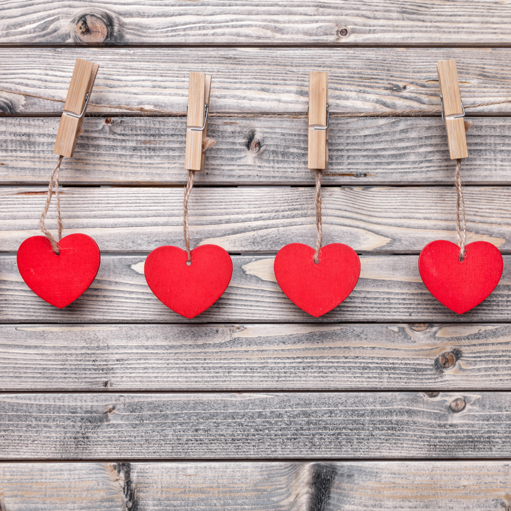 Красные сердечки на прищепках на деревянном столе 