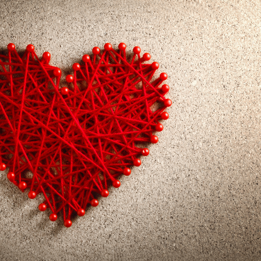 Сердце из красных нитей и невидимок на сером фоне