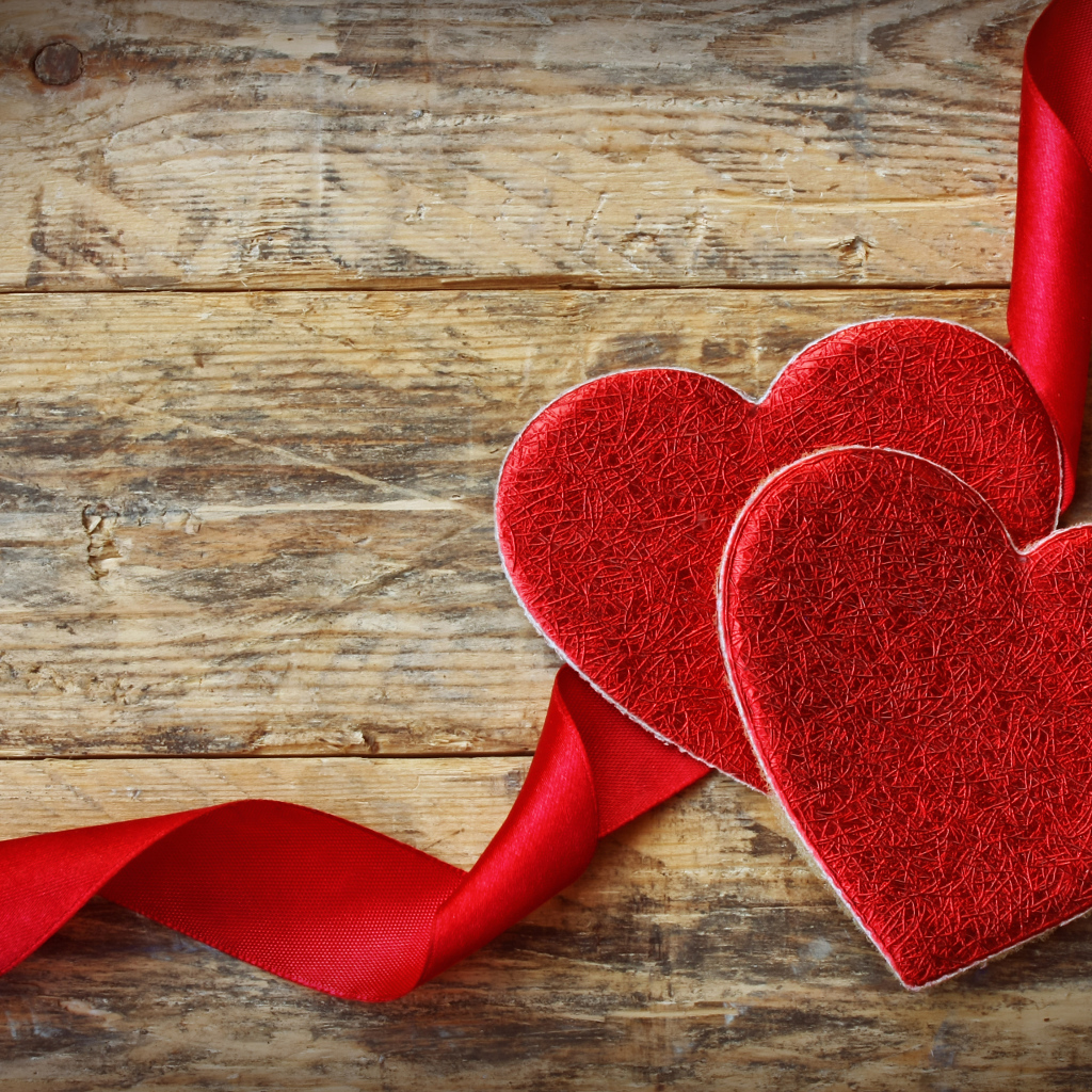Два сердца с красной лентой на деревянном столе