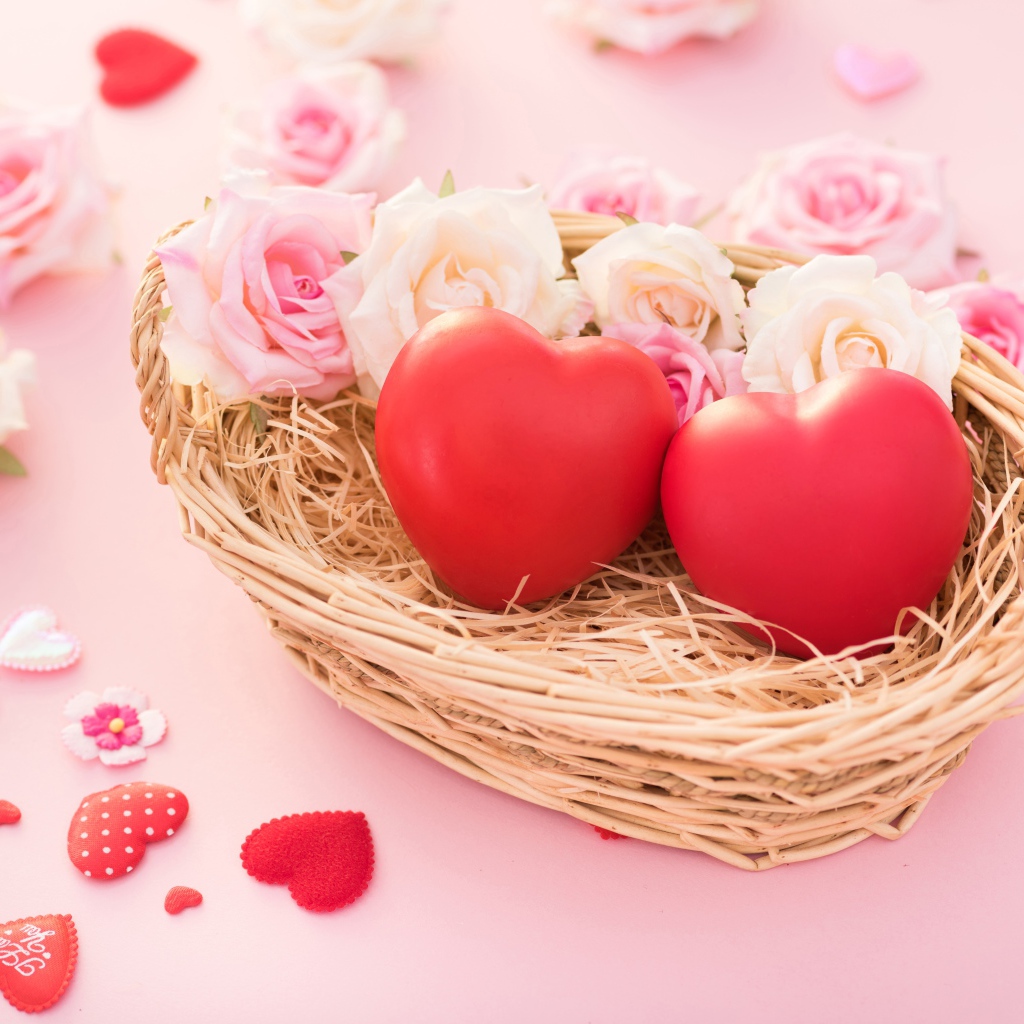 Два красных сердца лежат в корзинке с розами 