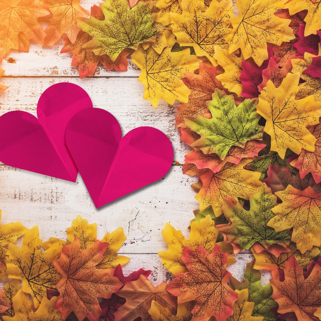 Два красных сердца на столе с желтыми листьями