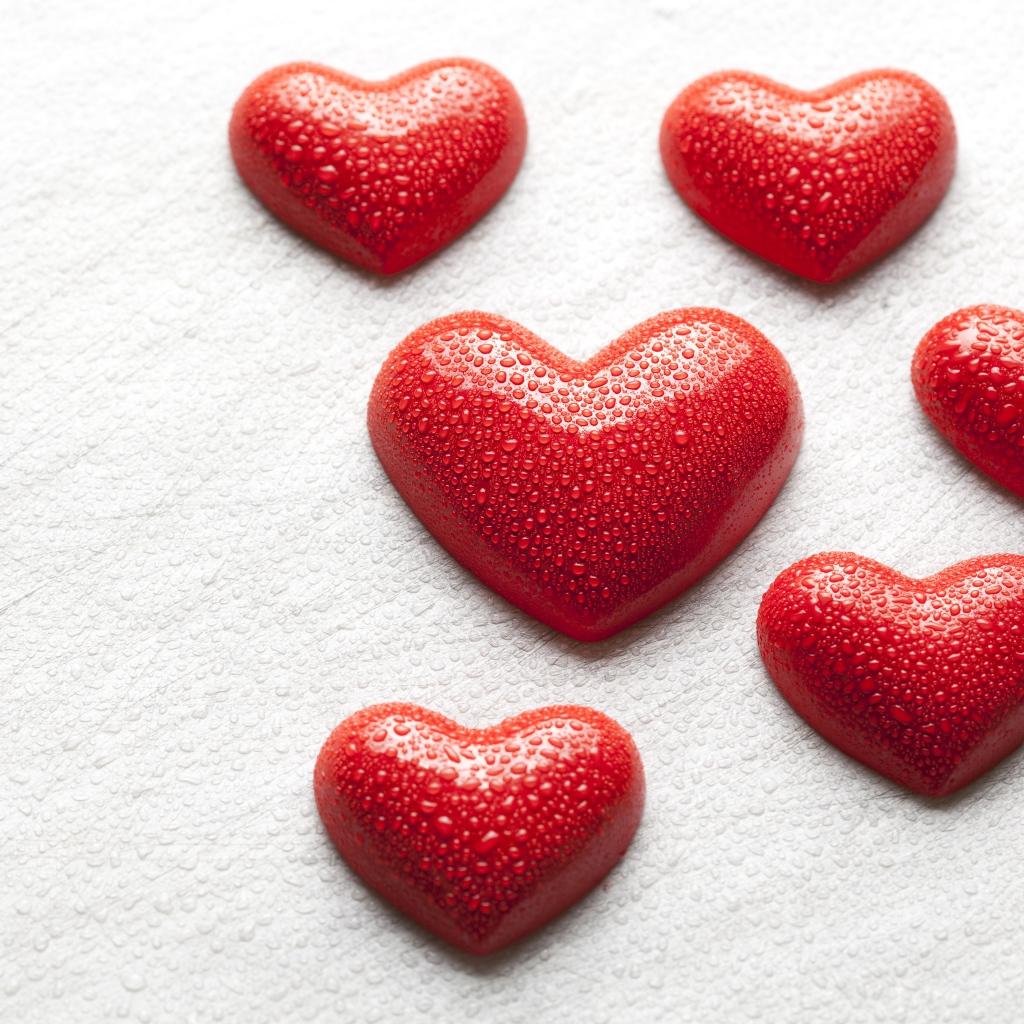 Мокрые красные сердечки на белой поверхности 