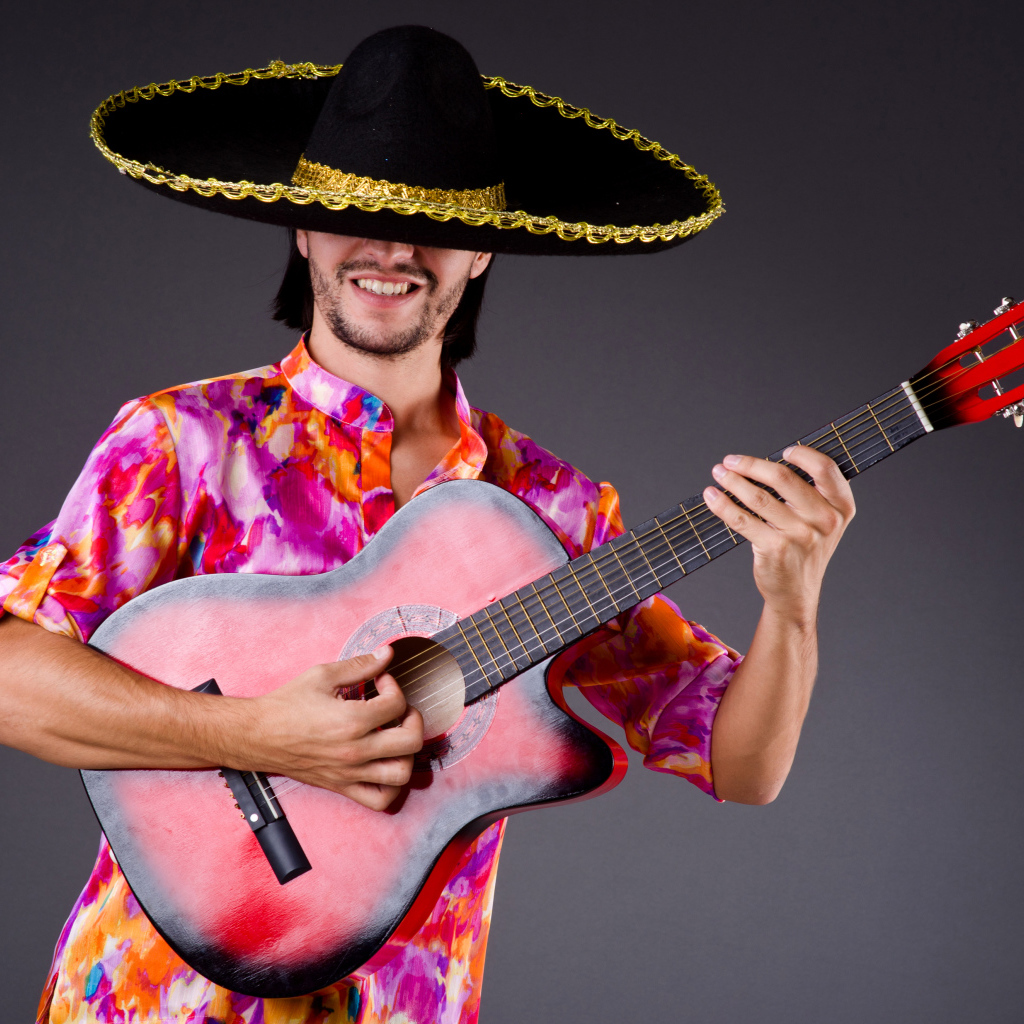 A man in a sombrero with a guitar in his hands on a gray background