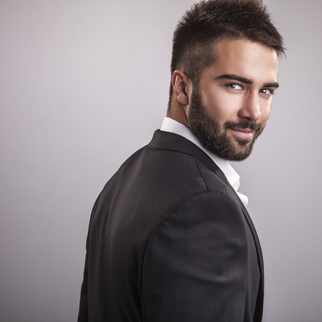 Handsome male model with a beard on gray background