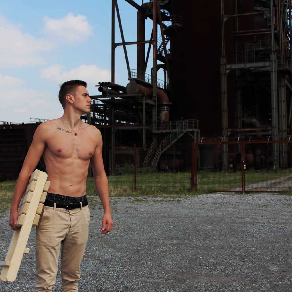 Красивый молодой парень стоит на фоне завода