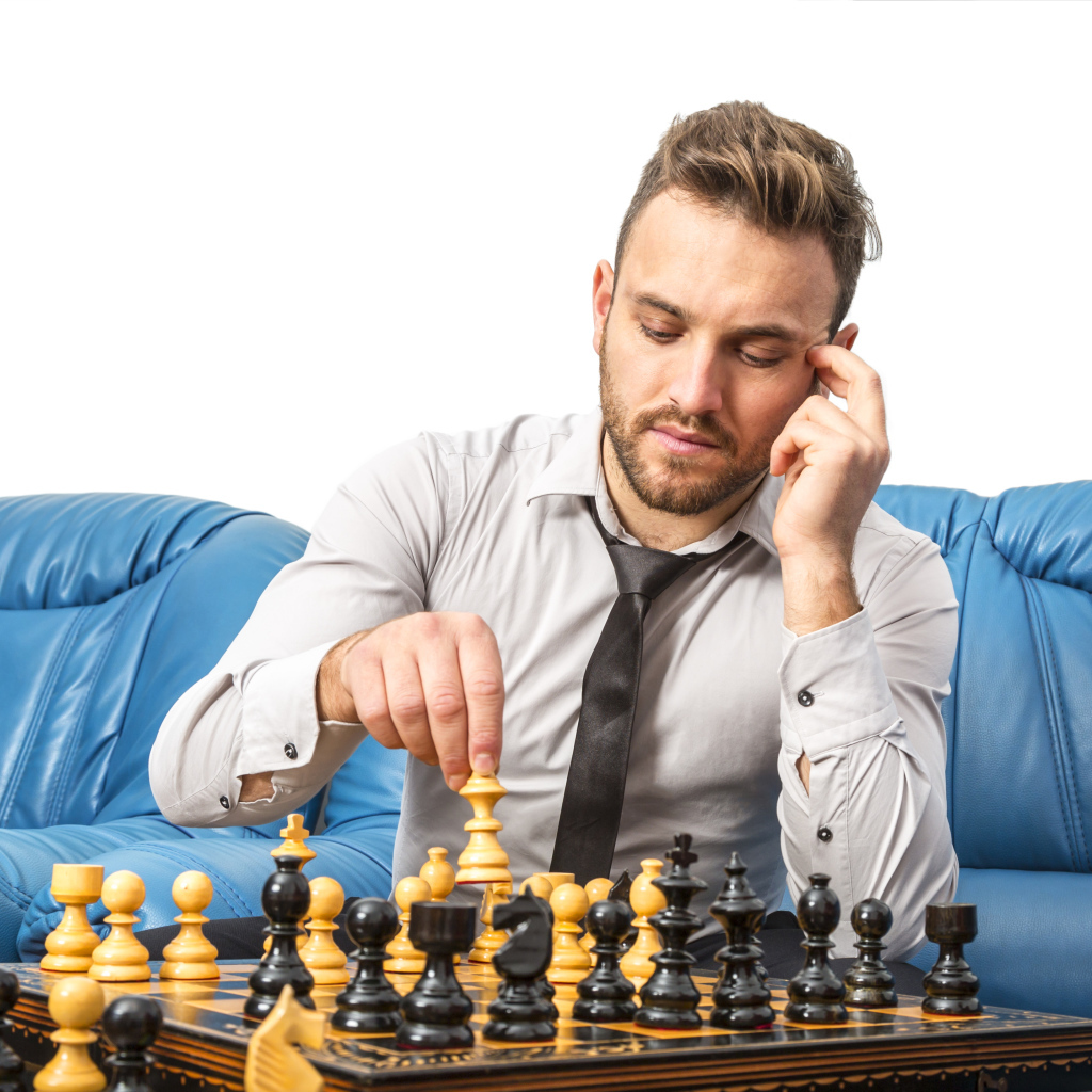 Мужчина играет в шахматы на синем диване