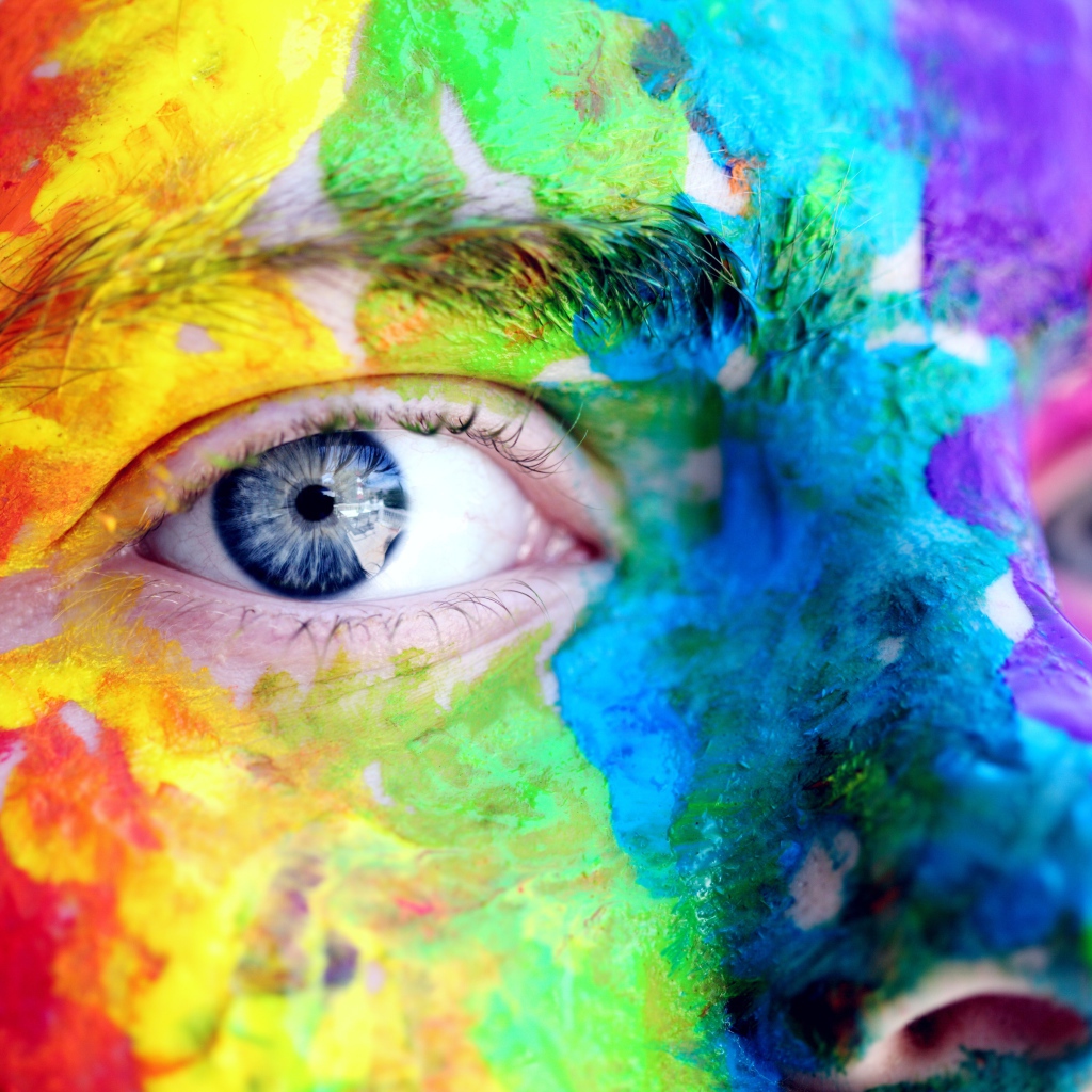Лицо голубоглазого мужчины в разноцветных красках крупным планом