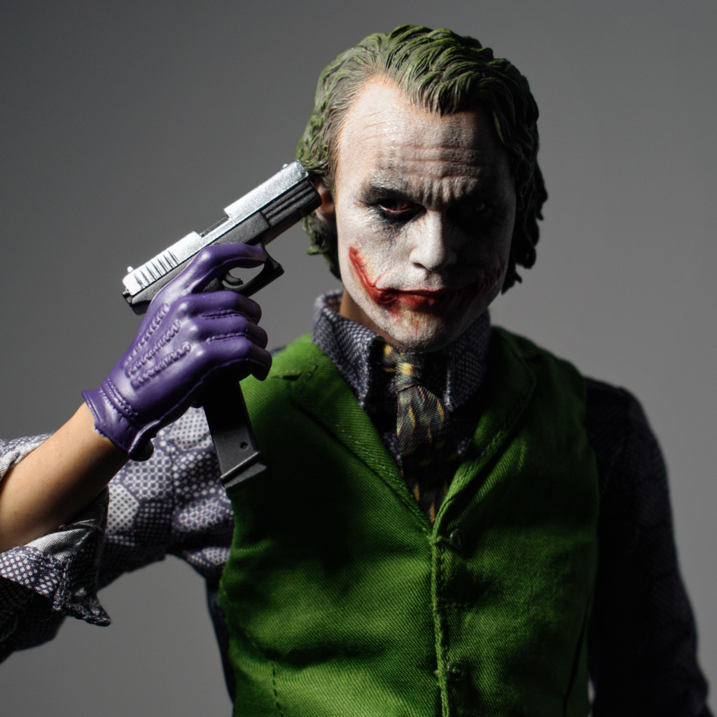 Персонаж Джокер с пистолетом в руке на сером фоне