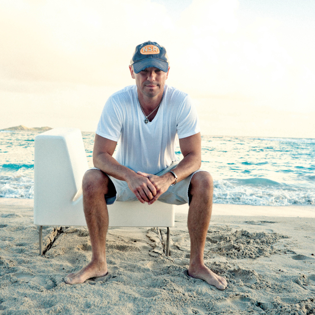 Исполнитель кантри Кенни Чесни на белом кресле на пляже