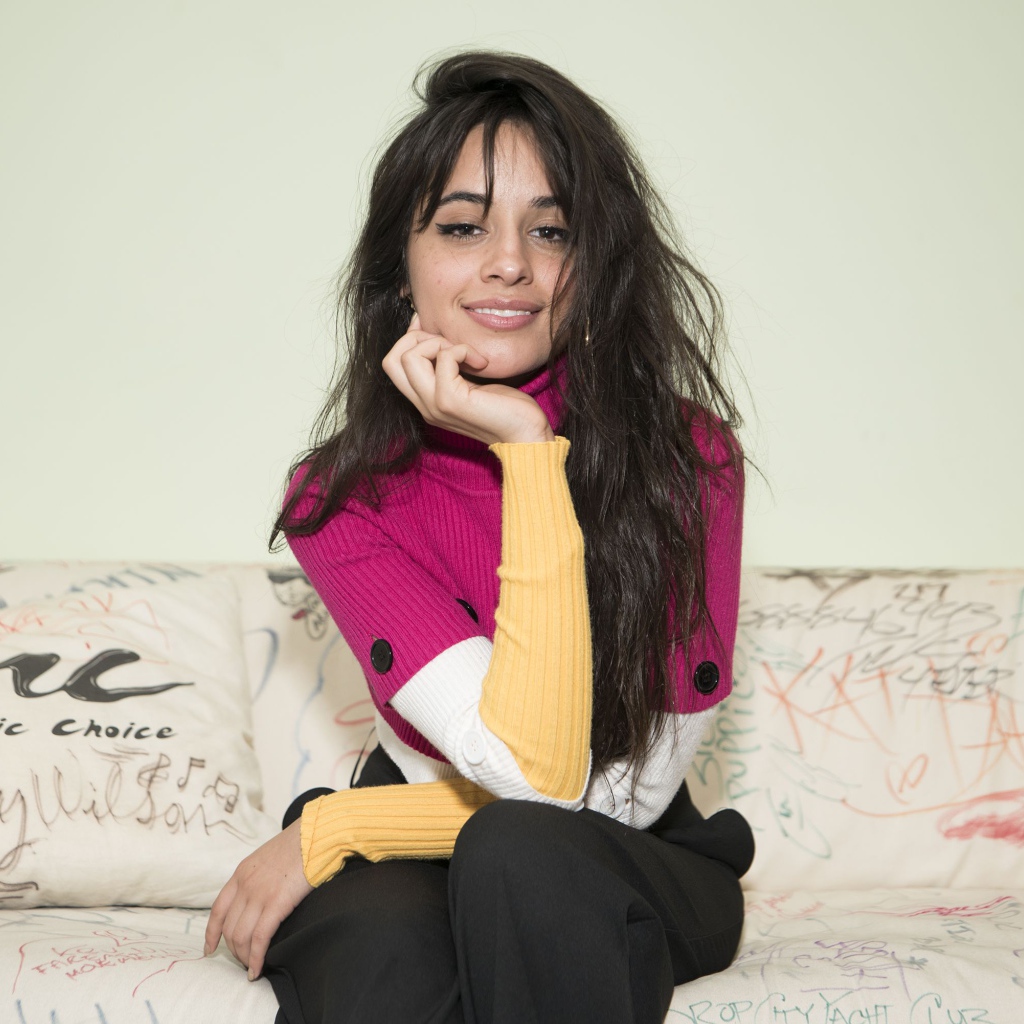 Улыбающаяся Камила Кабельо сидит на диване