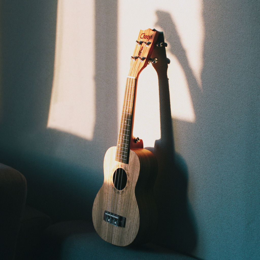 Желтая гитара стоит у серой стены