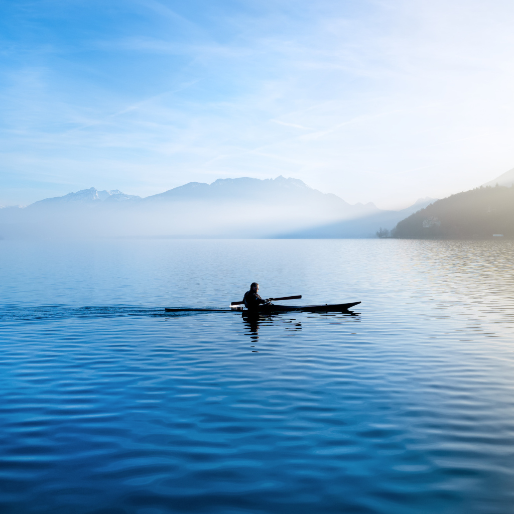 A man floats on a boat on the background of mountains