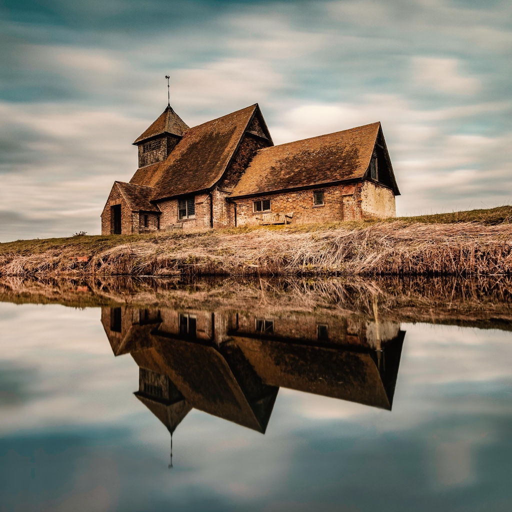 Старый дом на берегу реки отражается в воде